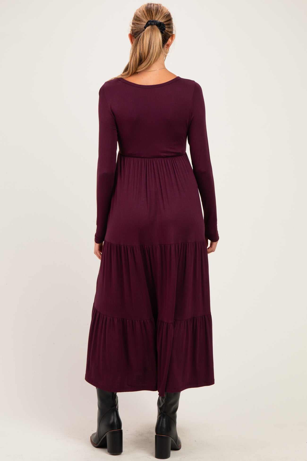 woman wearing a long sleeve burgundy maternity dress with tiered hemline and back view displayed