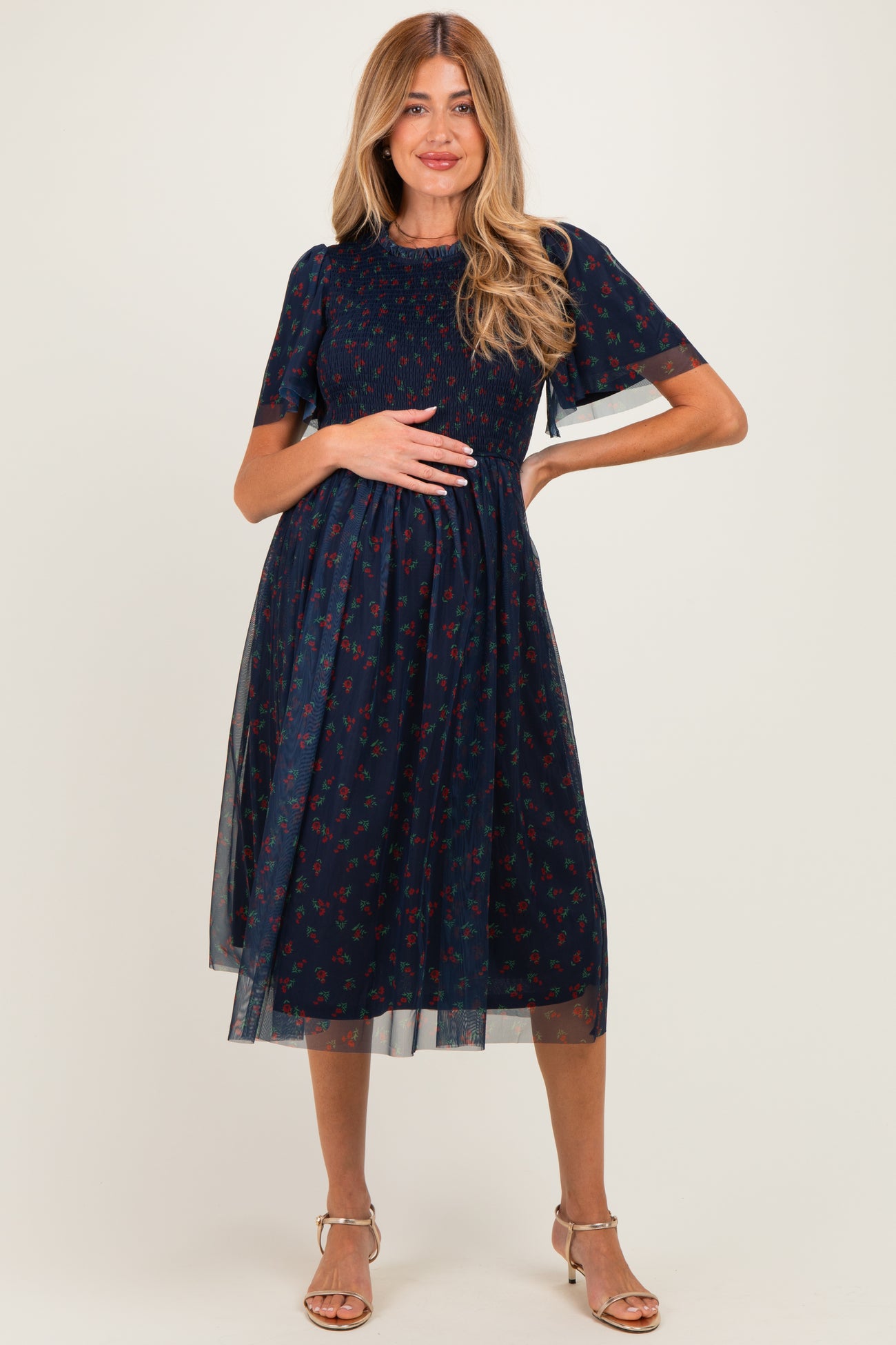 woman wearing a navy blue floral maternity dress with sheer sleeves and a baby bump visible