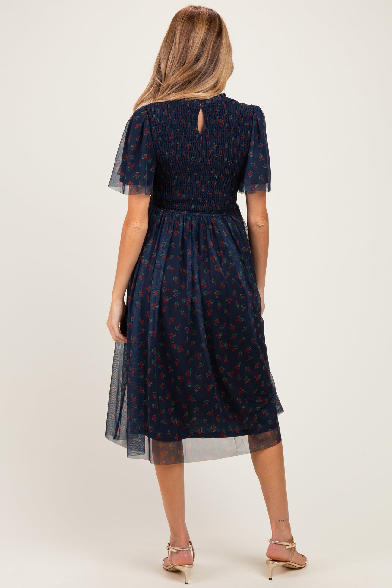 woman wearing a navy blue floral print maternity dress with short flutter sleeves and a smocked bodice