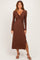 woman wearing a brown long sleeve maxi dress with a twist front and a side slit