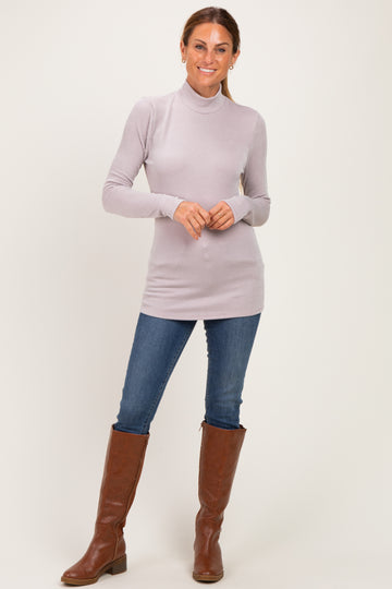 woman wearing a light purple ribbed turtleneck tunic top, paired with blue jeans and brown knee-high boots