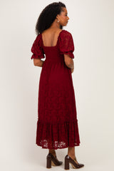 woman wearing a burgundy lace midi dress with puff sleeves and a tiered hem, viewed from the back