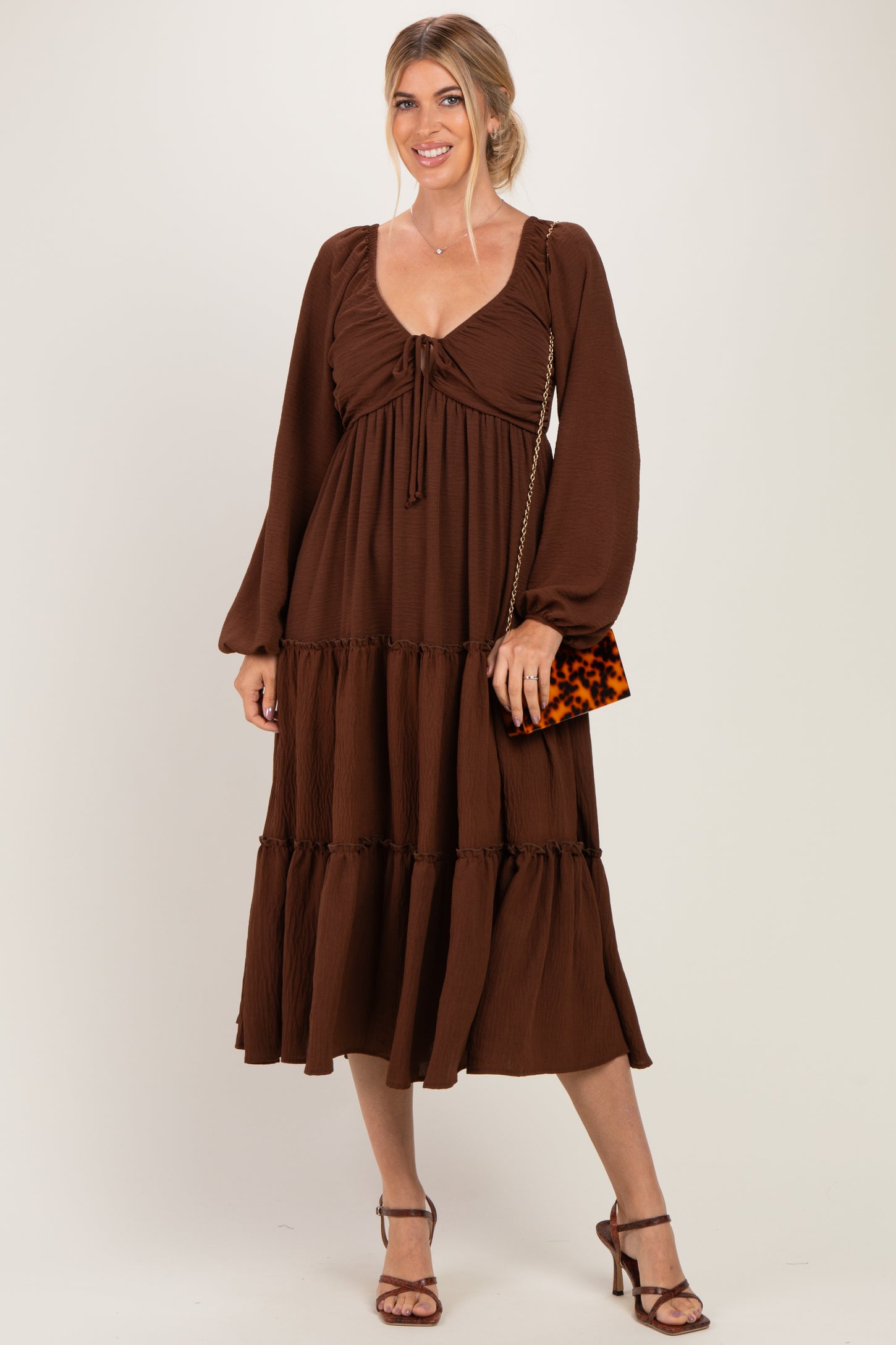 woman wearing a brown tiered maxi dress with long sleeves and a drawstring neckline