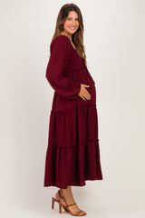 woman wearing a burgundy long sleeve maternity dress with tiered ruffles and a visible baby bump