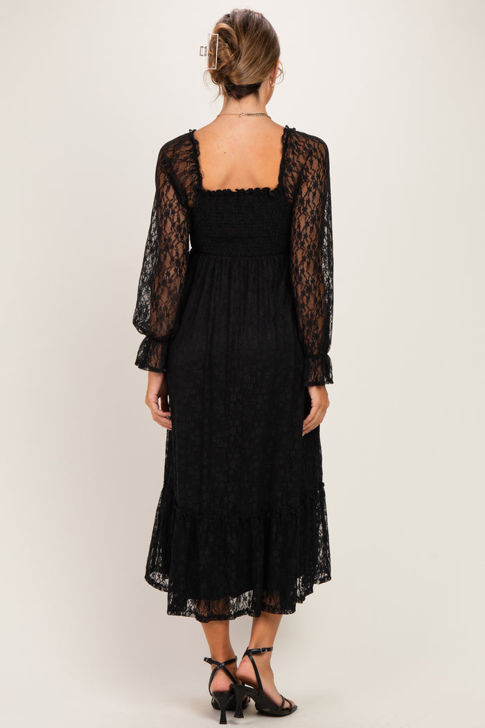 woman wearing a black lace maternity dress with long puff sleeves and a ruffled hem, showing a relaxed fit