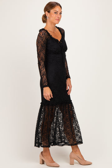 woman wearing a black lace long sleeve dress with a fitted bodice and flared hem, standing against a white background