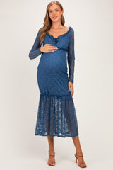 woman wearing a blue lace maternity dress with a ruffled hem and long sleeves, holding her baby bump