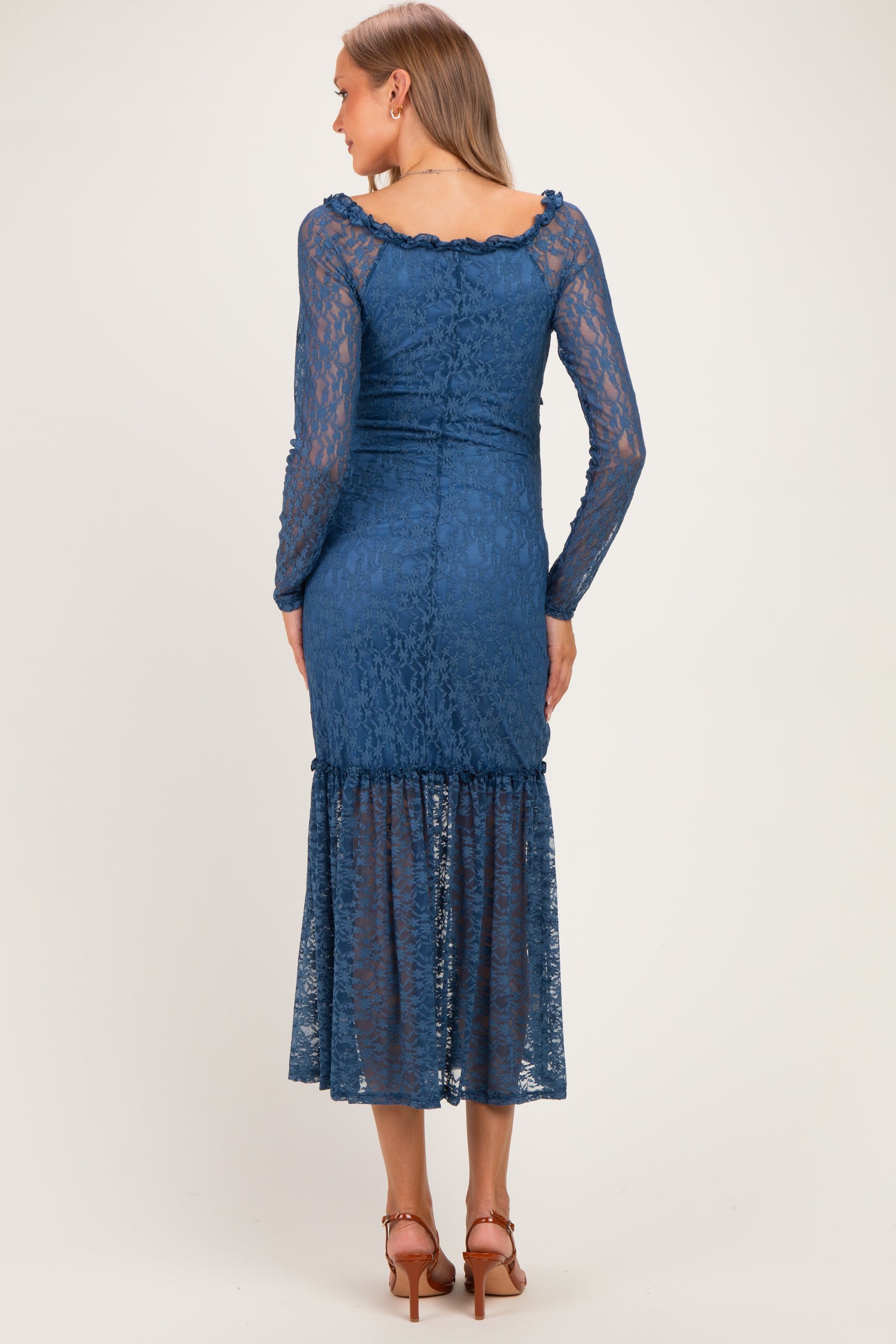 woman wearing a blue lace maternity dress with long sleeves and a ruffled hem, showing a pregnant belly from the back