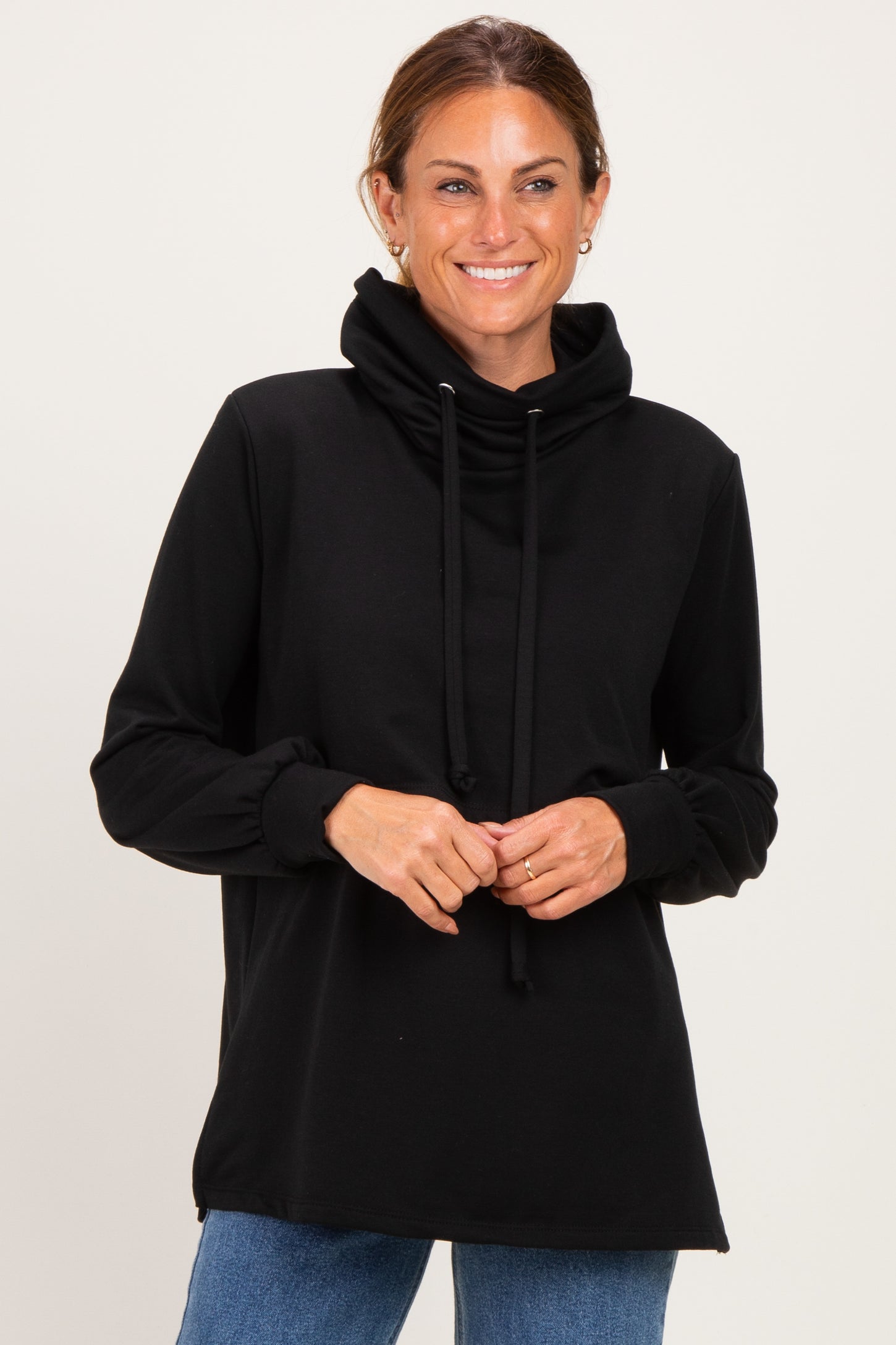woman wearing a black long sleeve hoodie with a cowl neck and drawstring, smiling at the camera