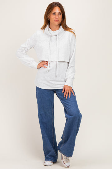 woman wearing a light gray cowl neck long sleeve crop sweatshirt paired with high-waisted blue wide-leg jeans