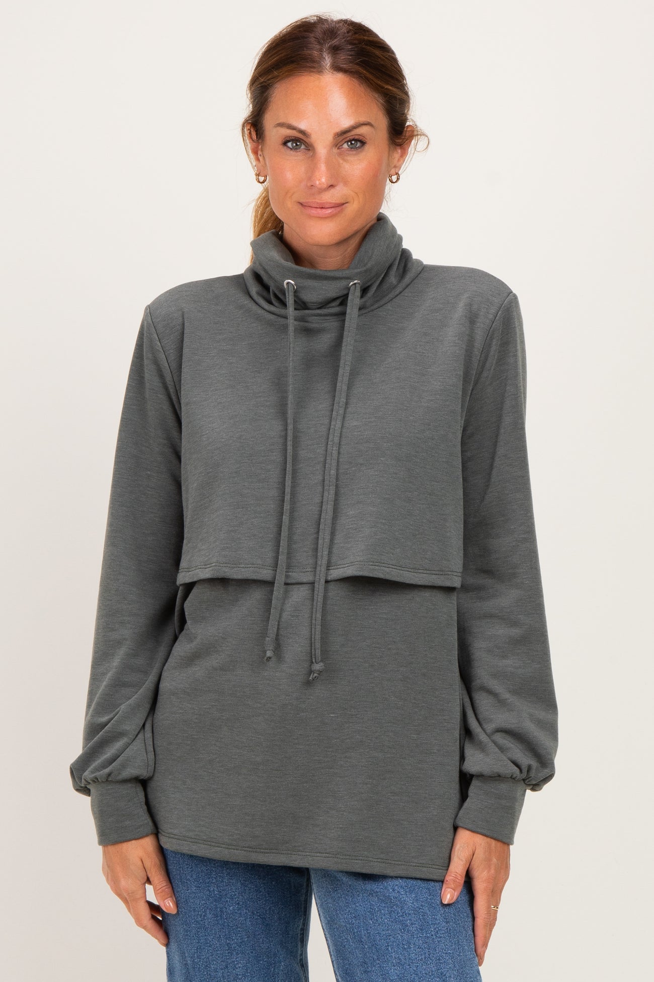 woman wearing a dark gray long sleeve cowl neck sweatshirt with a layered design and drawstring details