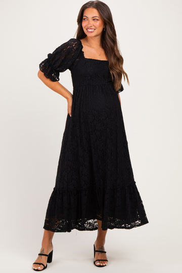 woman wearing a black lace maternity maxi dress with puff sleeves and a baby bump visible