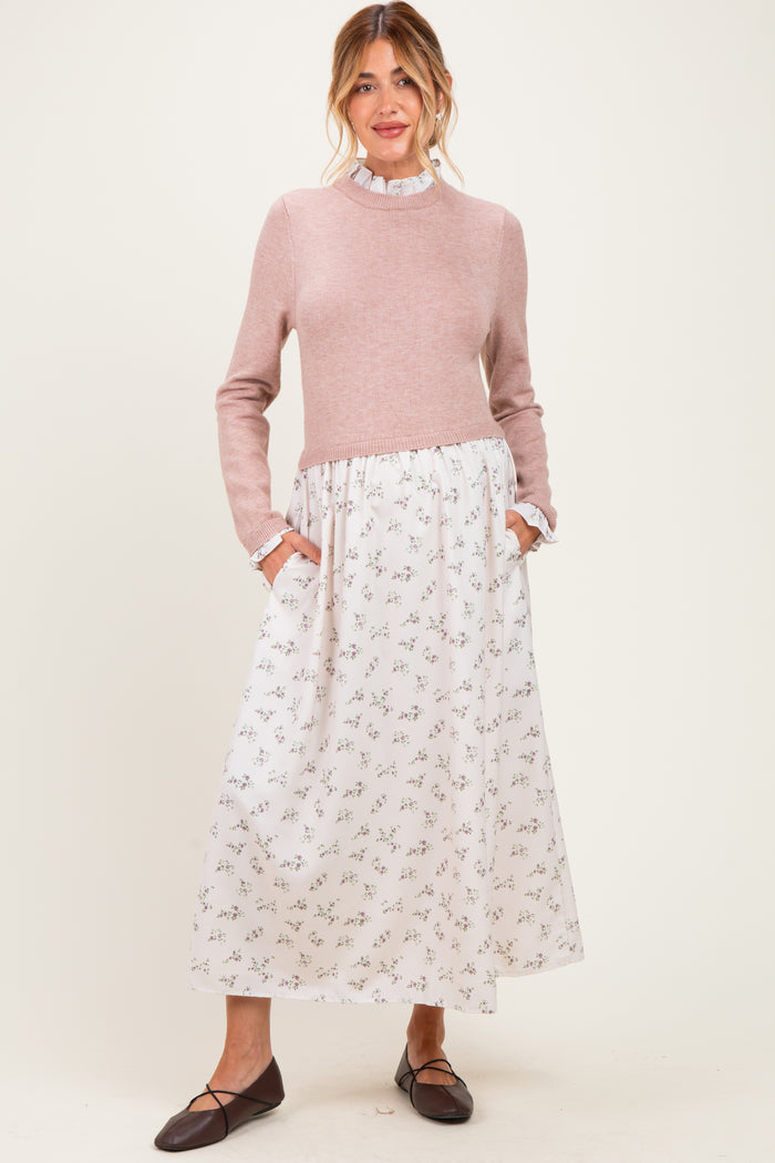 woman wearing a light pink maternity dress with a knitted top and floral print skirt, featuring pockets and ruffled details