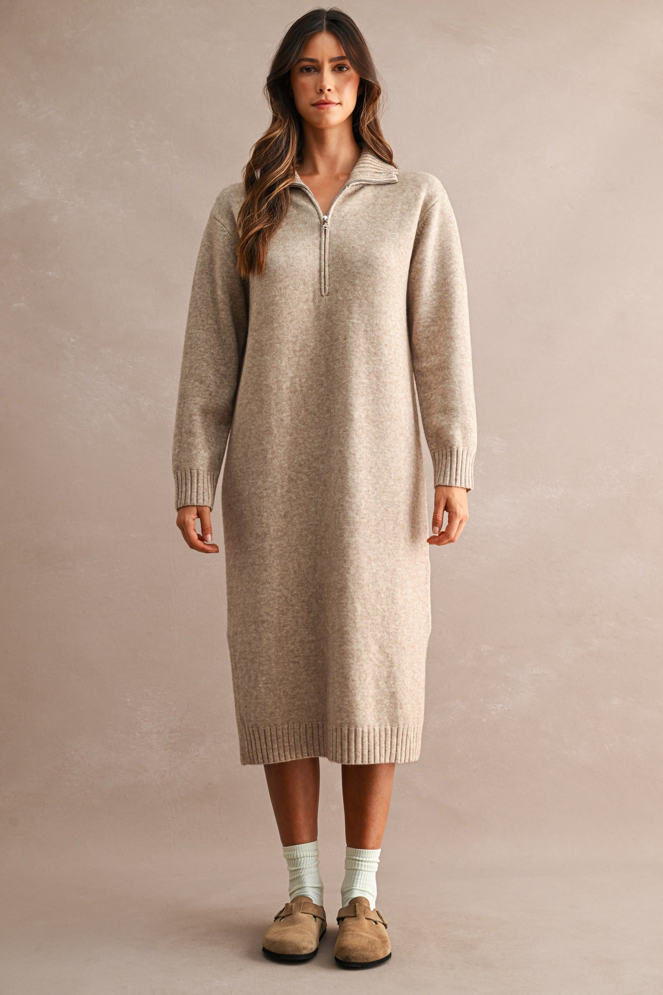 woman wearing a beige long sleeve zip-up sweater dress with ribbed details and a relaxed fit