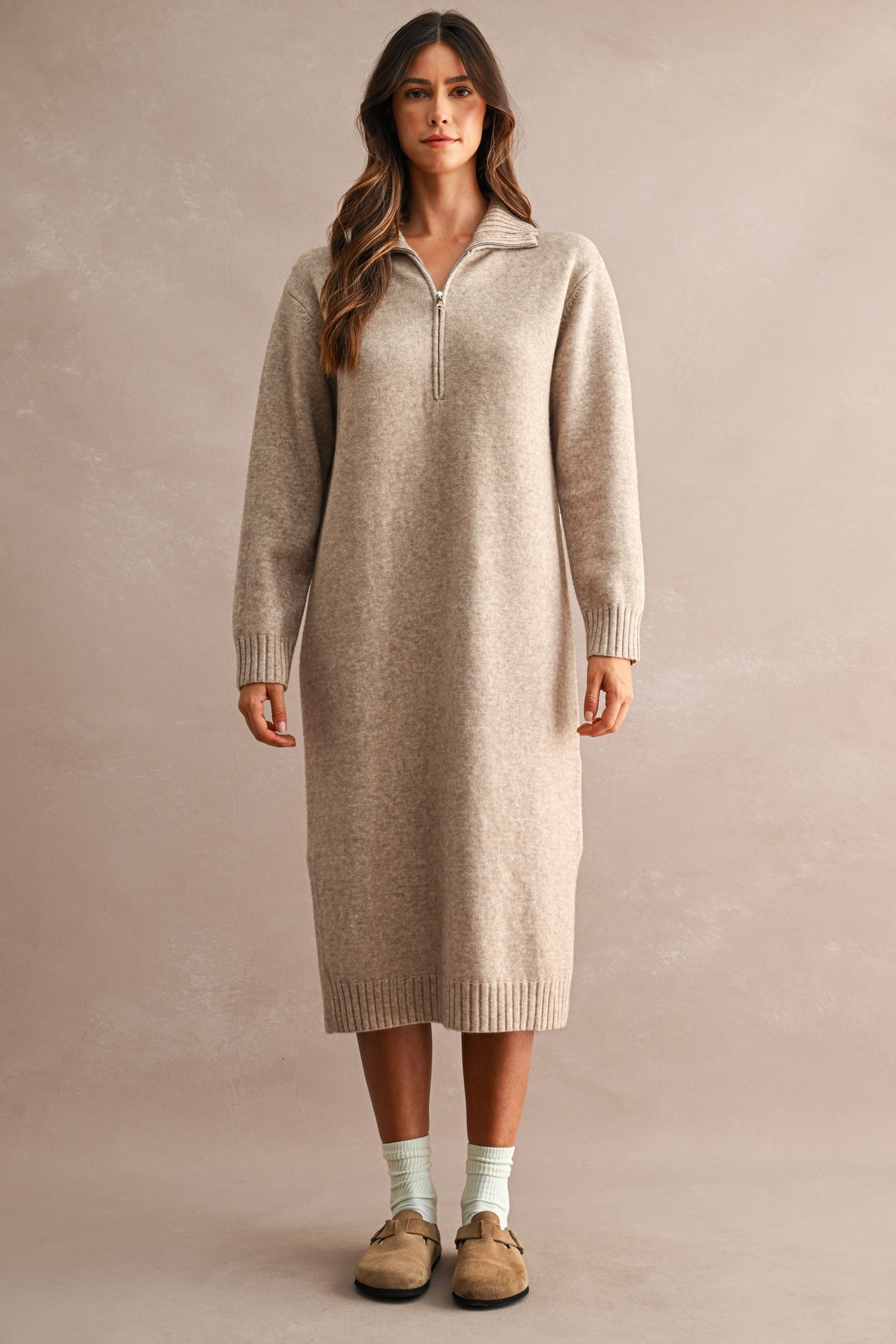woman wearing a beige long sleeve zip-up sweater dress with ribbed details and a relaxed fit