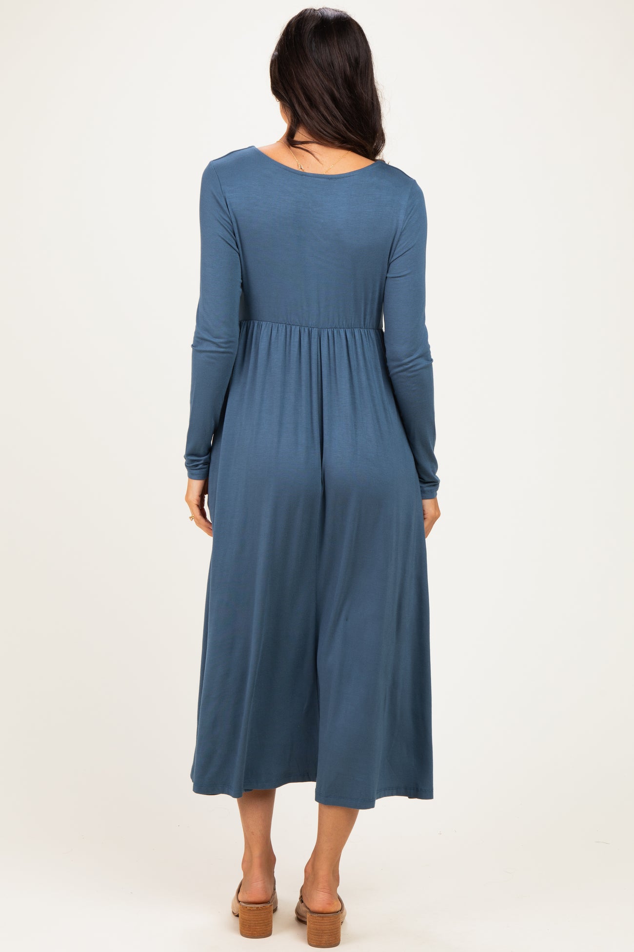 woman wearing a long sleeve blue midi dress with a fitted waist and relaxed skirt, seen from the back