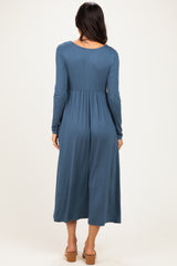 woman wearing a long sleeve blue midi dress with a fitted waist and relaxed skirt, seen from the back