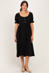 woman wearing a black midi dress with puff sleeves and button details in the front