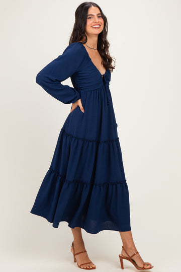 woman wearing a navy blue long sleeve tiered maxi dress with a tie-front detail and relaxed fit