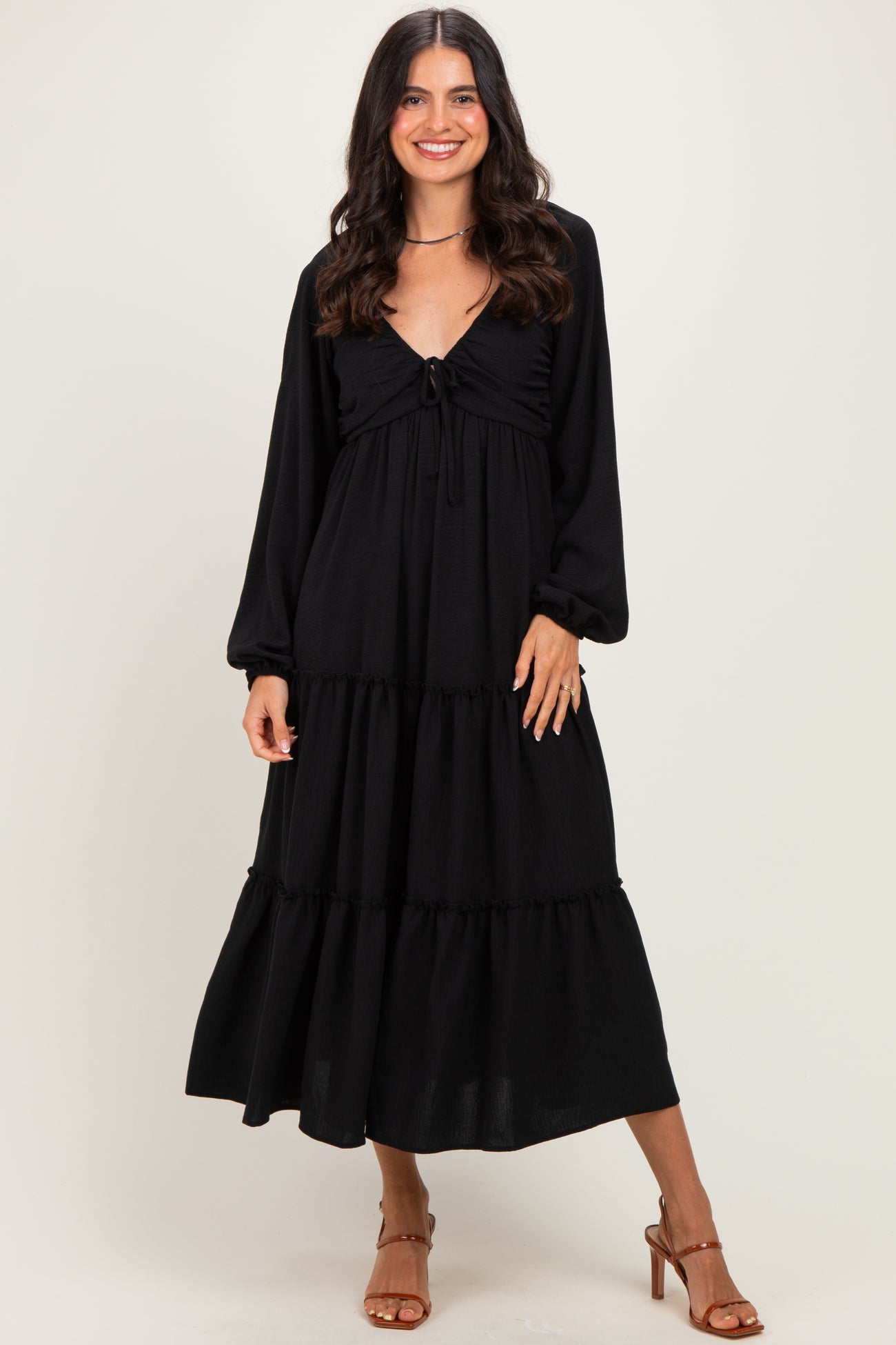 woman wearing a black long sleeve maxi dress with a tie-front and tiered skirt
