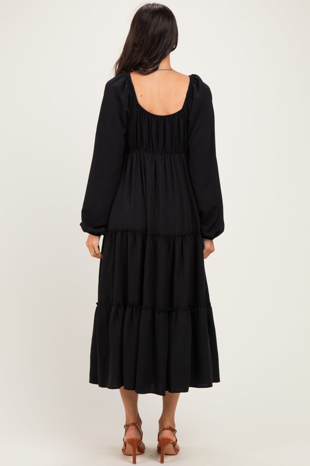 woman wearing a black long sleeve tiered dress with a backless design and puffed sleeves