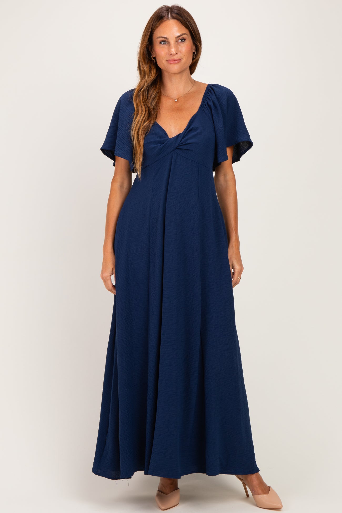 woman wearing a navy blue maxi dress with short flutter sleeves and a fitted bodice