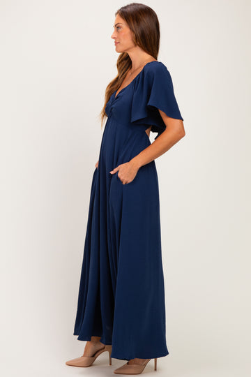 woman wearing a navy blue maxi dress with flutter sleeves and side pockets