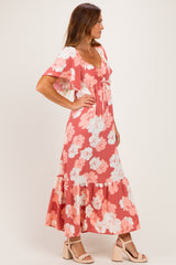 woman wearing a coral floral maxi dress with flutter sleeves and a tie-front detail