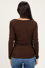 woman wearing a brown long sleeve ribbed top with a fitted style and gathered detail at the sides