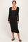 woman wearing a fitted black ribbed long sleeve dress with a square neckline and midi length, standing against a neutral background