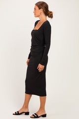 woman wearing a black long sleeve ribbed dress with a square neckline and side ruching, styled with black heeled sandals