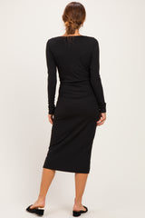 woman wearing a black ribbed long sleeve midi dress, view shows the back and wrist detail, paired with black sandals
