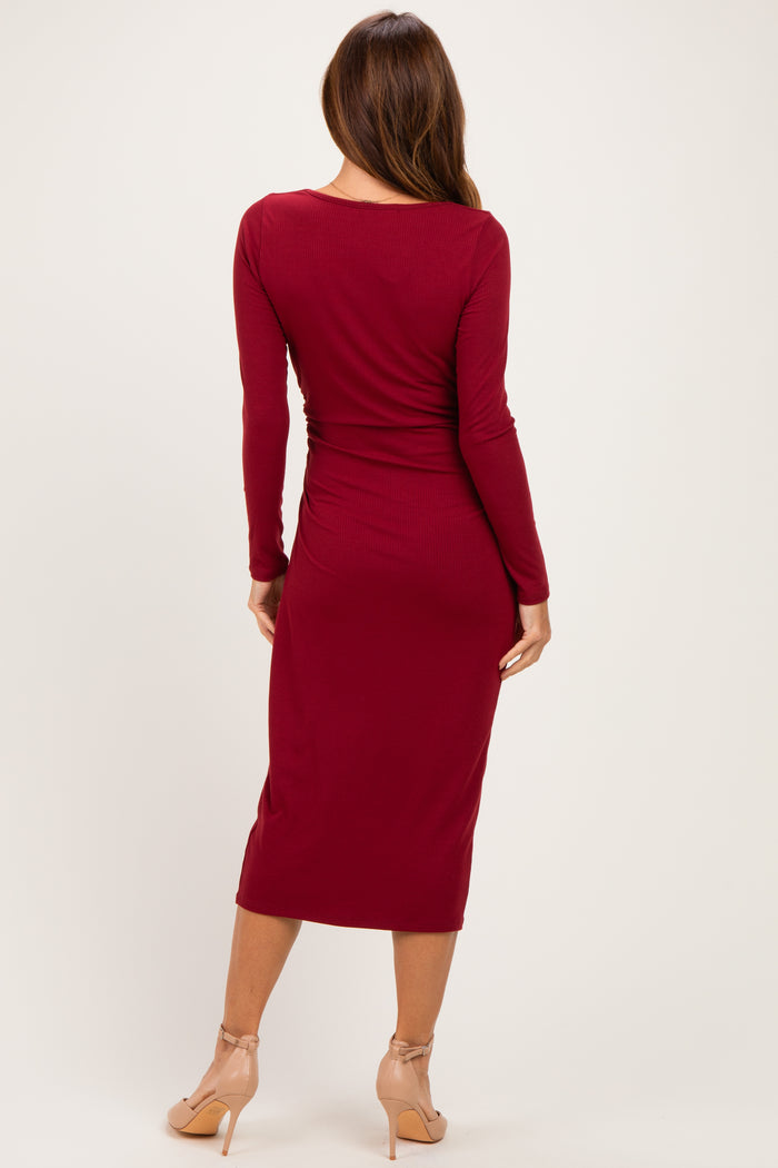 woman wearing a burgundy long sleeve midi dress with a fitted silhouette and back ruching detail