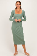 woman wearing a long sleeve ribbed midi dress in sage green with a square neckline and gathered side details