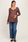 woman wearing a brown maternity long sleeve top with floral print and buttons, holding her baby bump, paired with blue jeans