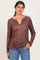 woman wearing a brown long sleeve henley top with a floral print and gathered sides, paired with light blue jeans