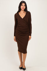 woman wearing a brown long sleeve wrap dress with ruched detailing and a fitted silhouette