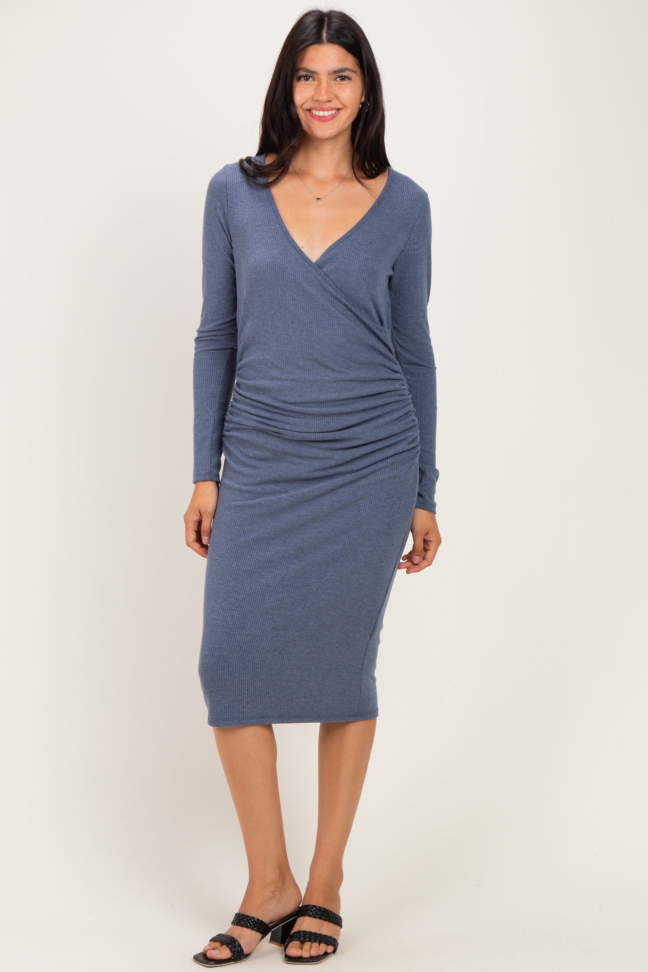 woman wearing a blue long sleeve wrap dress with ruched detailing and a knee-length hem