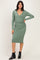 woman wearing a green long sleeve wrap dress with ruching and a v-neck, standing with one hand on her hip