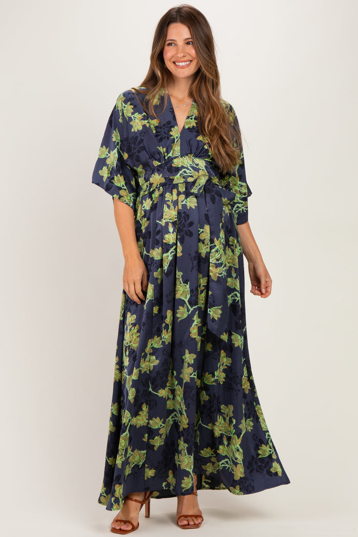woman wearing a navy blue floral maternity maxi dress with a cinched waist and flutter sleeves, showcasing her baby bump