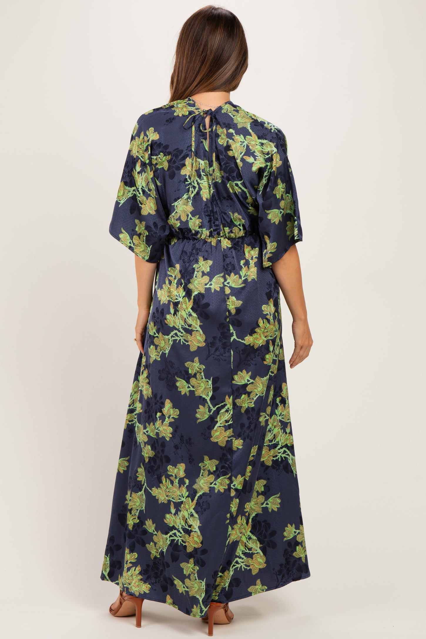 woman wearing a navy blue floral maternity maxi dress with a cinched waist and open back design