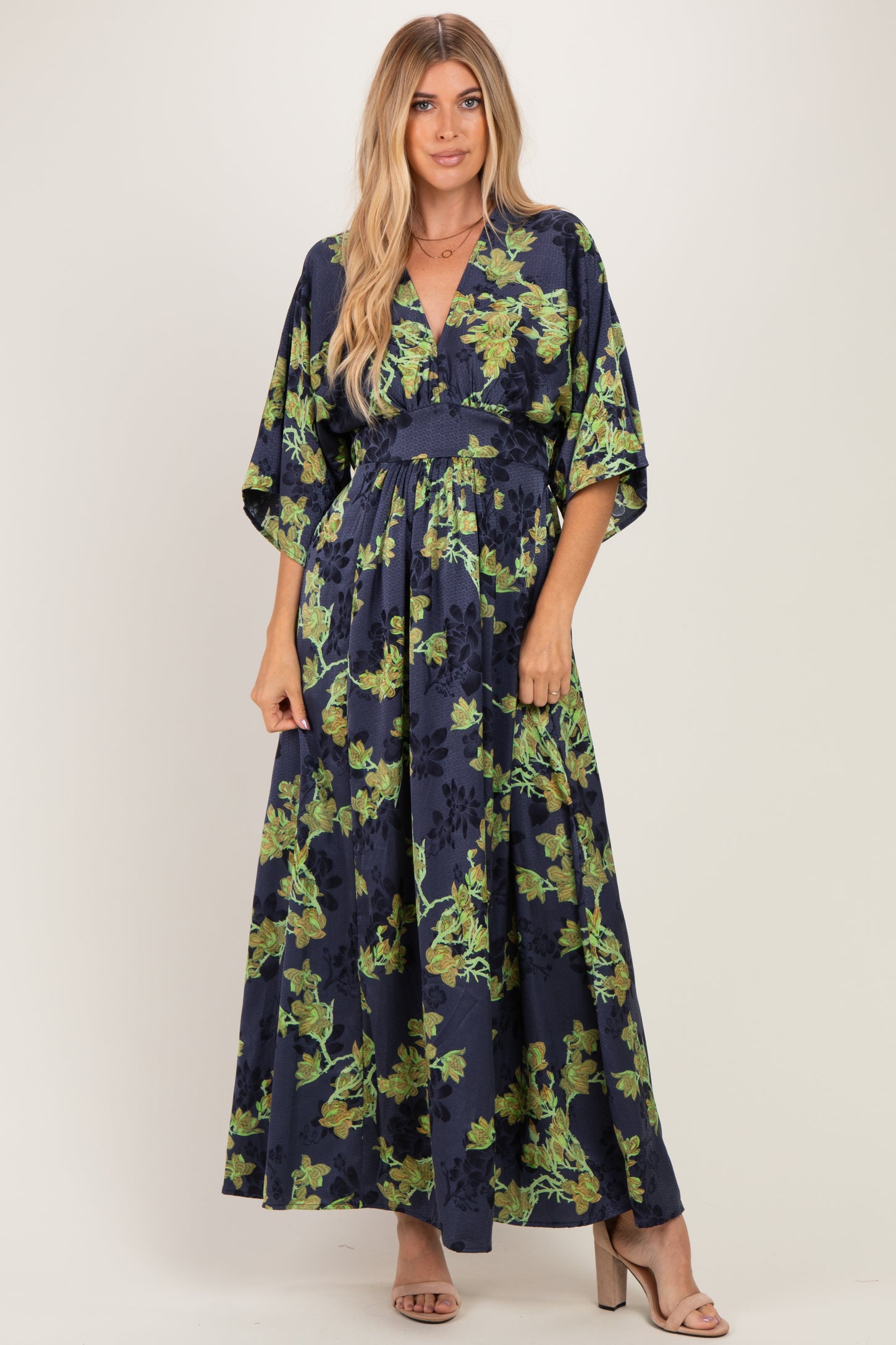 woman wearing a navy blue maxi dress with floral print and kimono sleeves, styled with heels