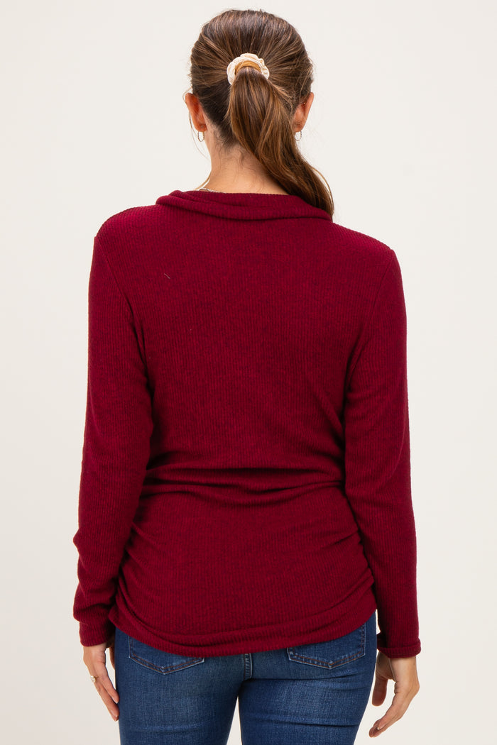 woman wearing a burgundy maternity top with a cowl neck and gathered sides, showing a relaxed fit from the back