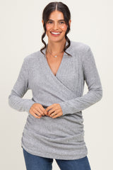woman wearing a gray ribbed wrap top with long sleeves and a relaxed fit, smiling at the camera