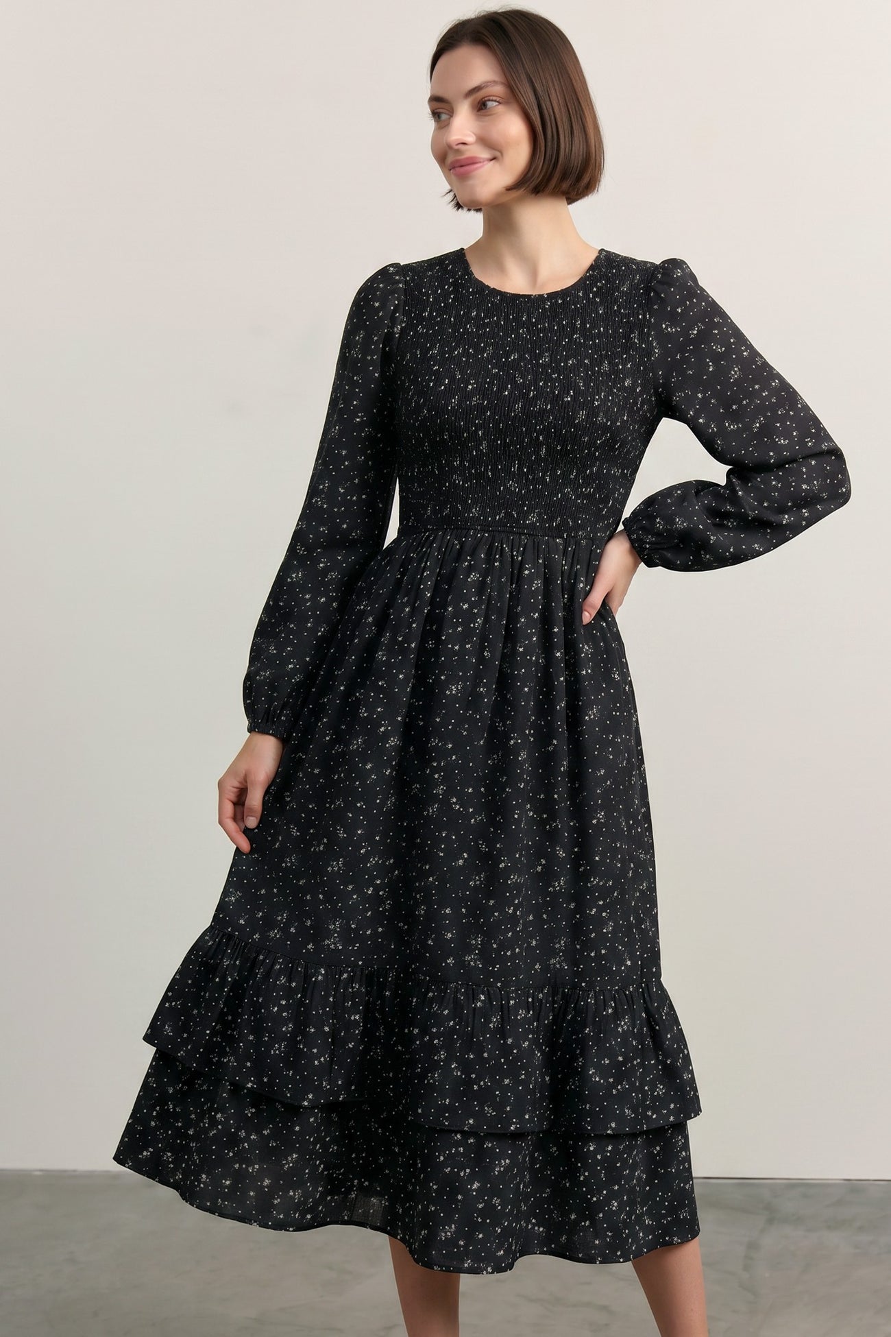 woman wearing a black floral long sleeve dress with smocked bodice and tiered ruffle hem