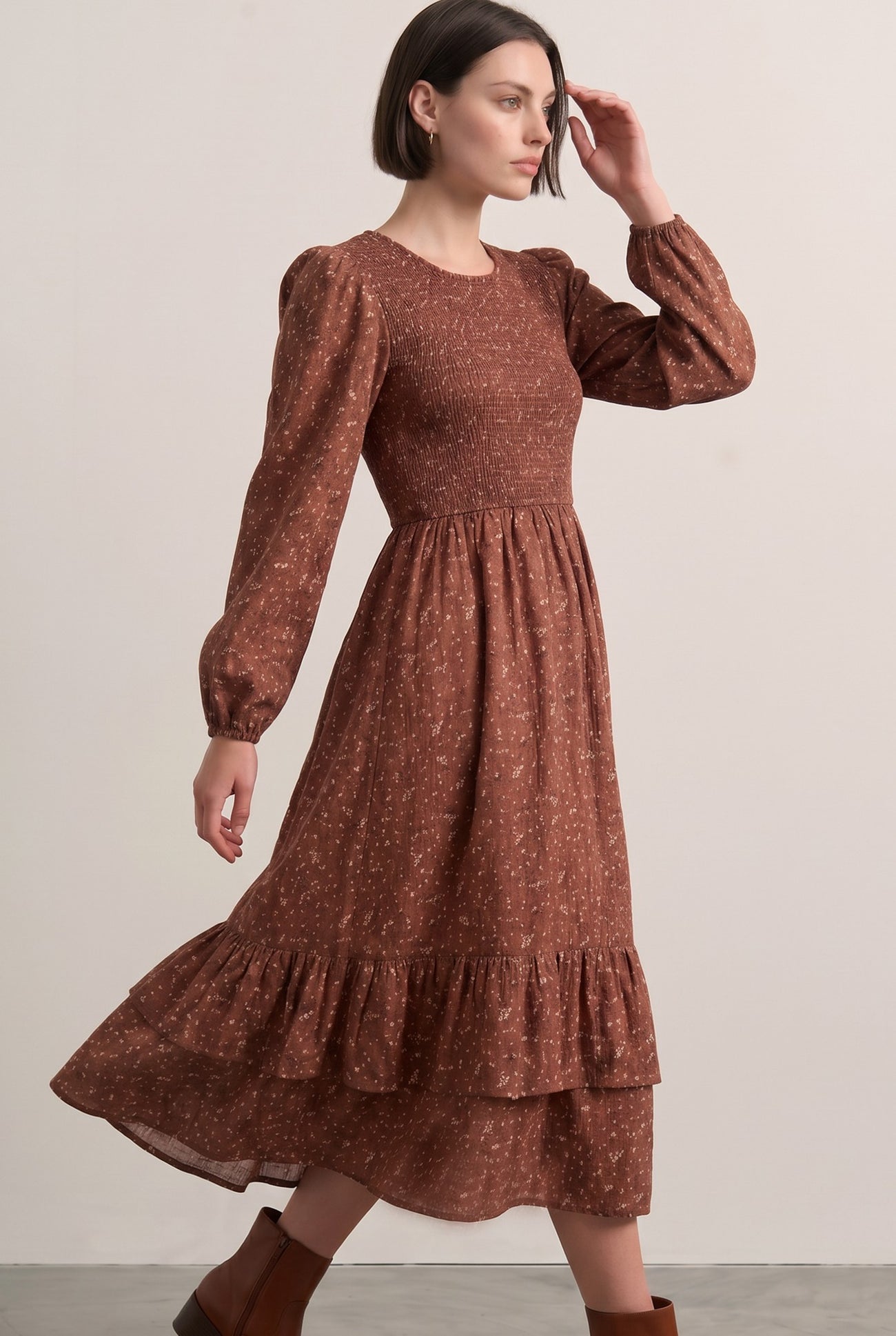 woman wearing a brown floral print midi dress with puff sleeves and a tiered ruffle hem