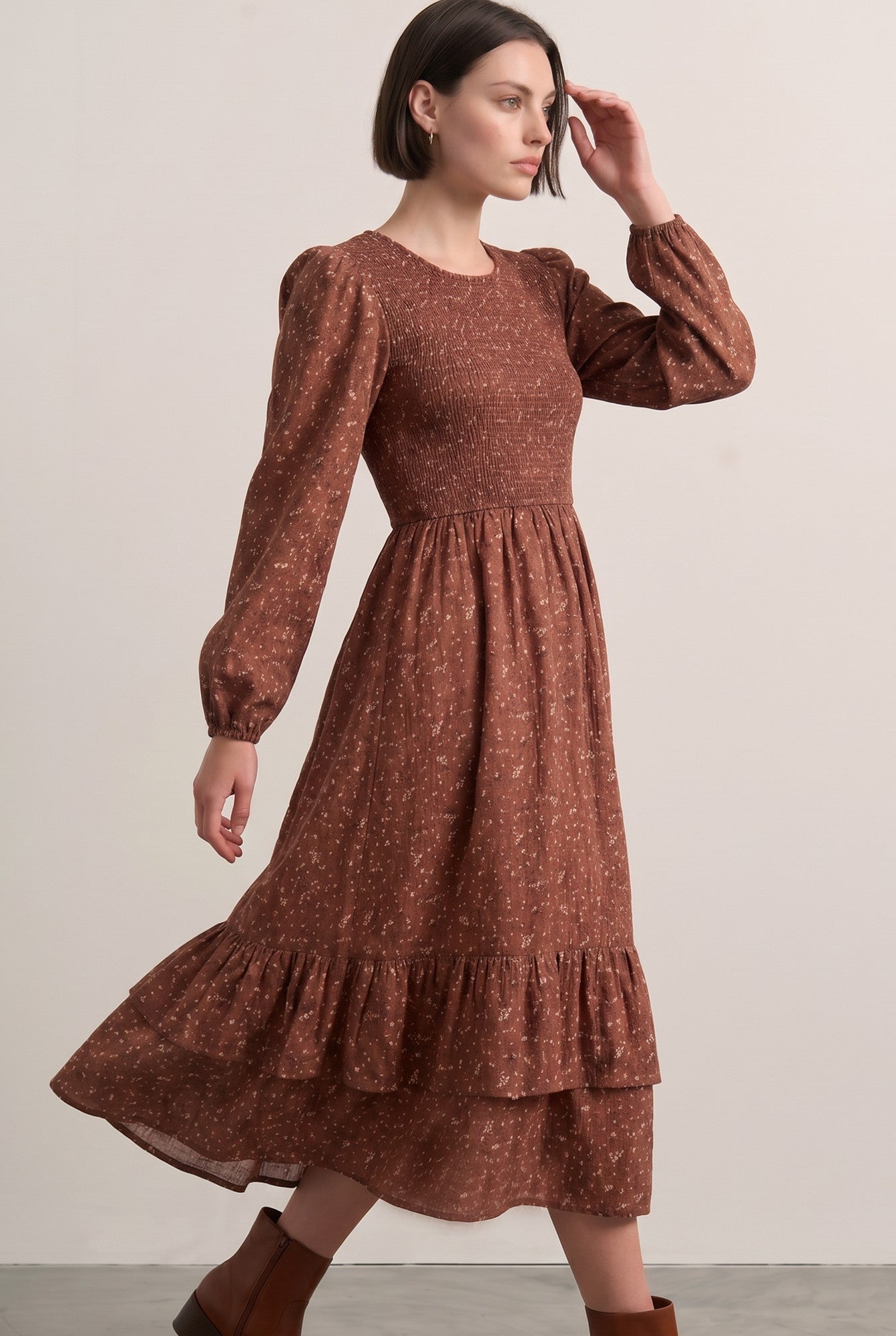 woman wearing a brown floral print midi dress with puff sleeves and a tiered ruffle hem