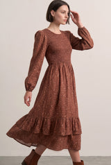 woman wearing a brown floral print midi dress with puff sleeves and a tiered ruffle hem