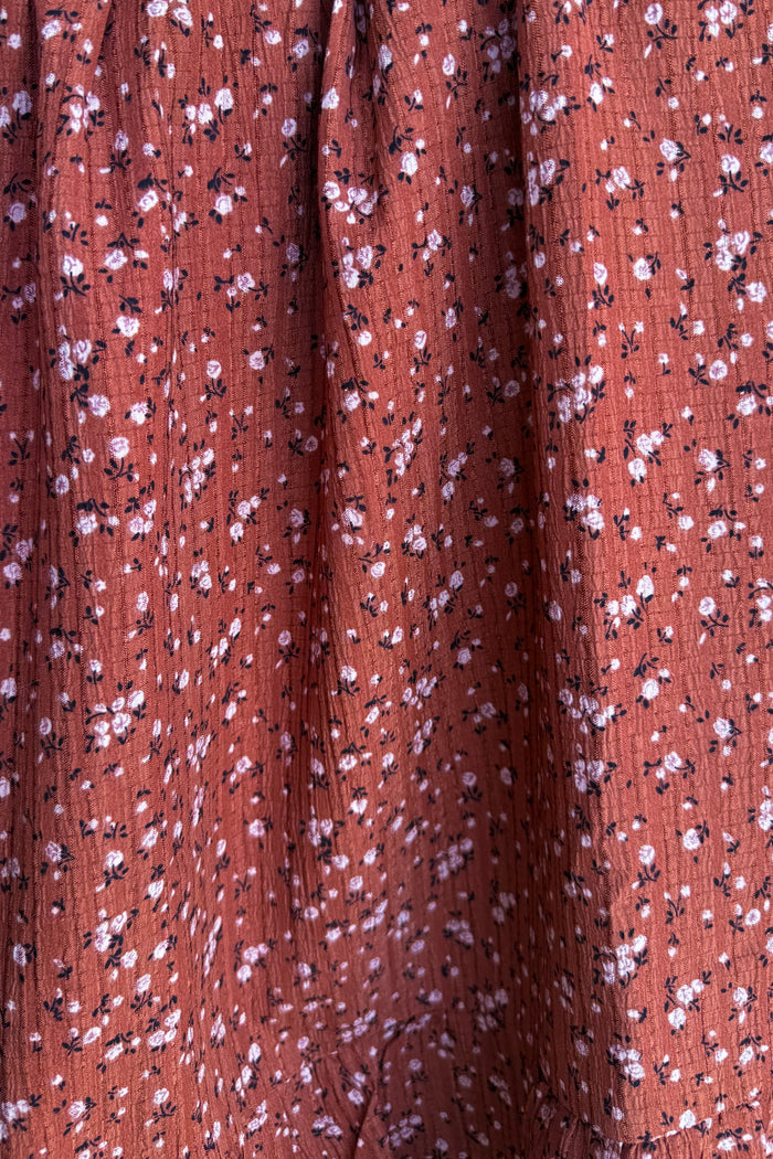 rust floral print fabric with small pink and white flowers on a textured background
