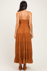 woman wearing a rust-colored backless maxi dress with a smocked bodice and tiered lace hem